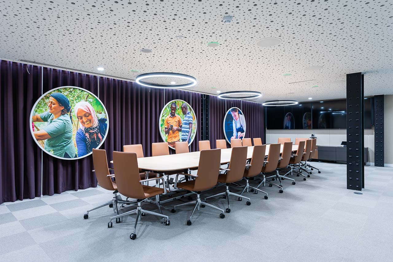 Boardroom with long meeting table and presenting screens with feature ceiling and lighting